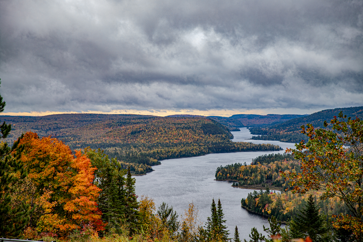 Lago in autunno circondato da alberi con foglie arancioni, gialle rosse in Canada